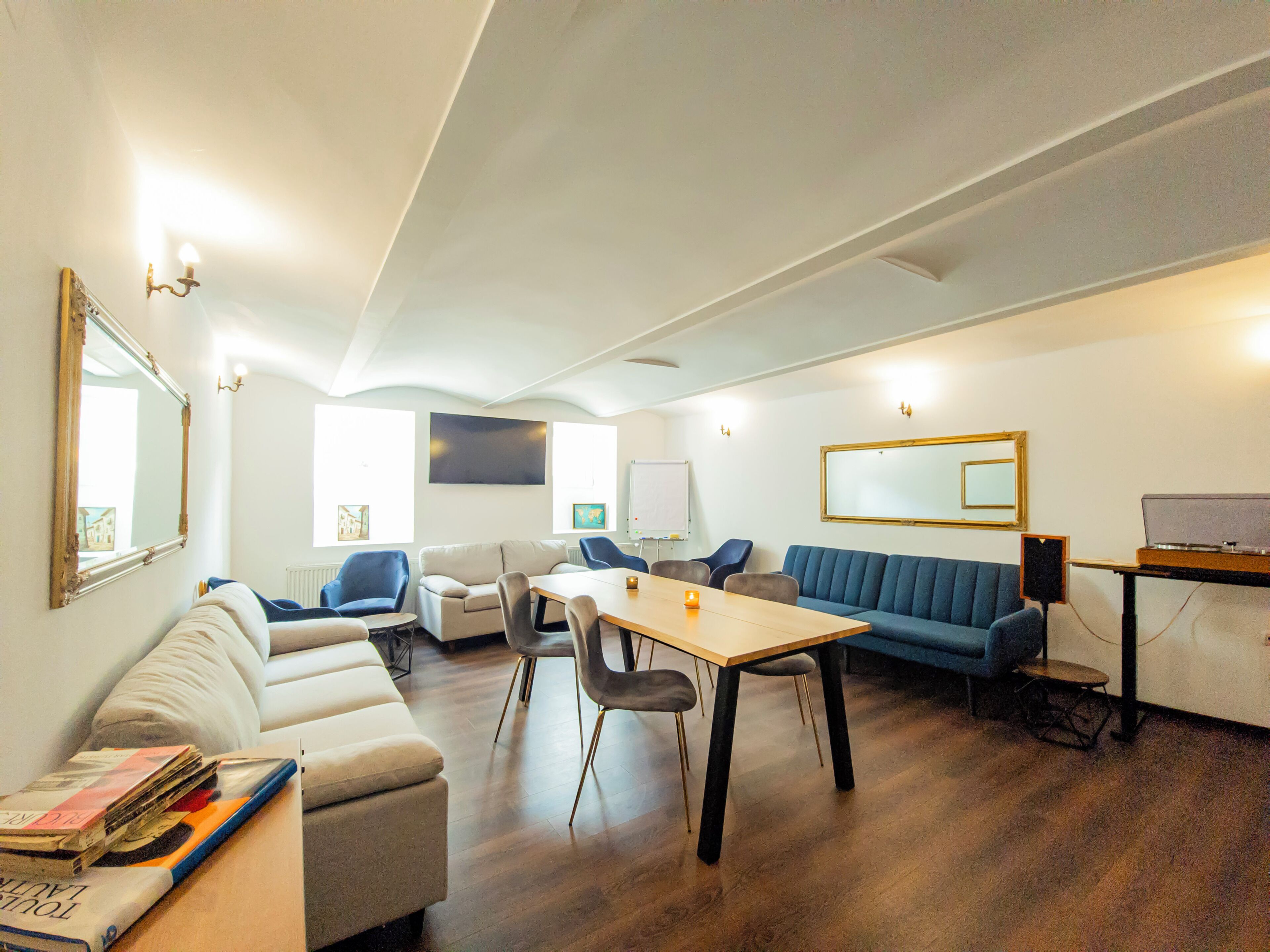 Una habitación moderna con sofá, sillas, una mesa y un ordenador portátil sobre un atril.