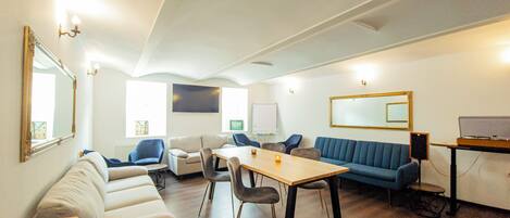 Una habitación moderna con sofá, sillas, una mesa y un ordenador portátil sobre un atril.