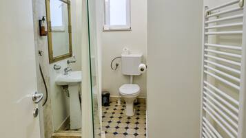 Un baño con cabina de ducha de vidrio, inodoro blanco y lavabo.