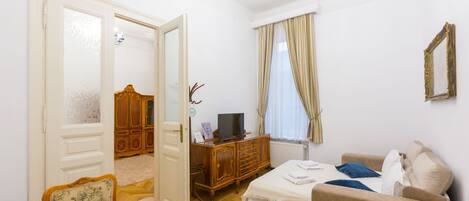 Una habitación de hotel con una mesa de comedor de madera, un sofá, un televisor y un armario.