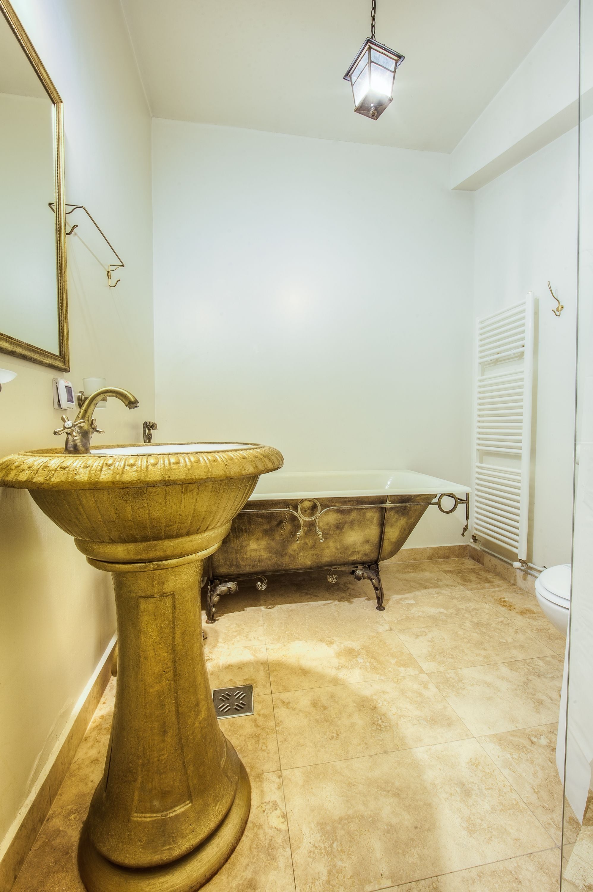 A bathroom with a pedestal sink, a freestanding bathtub, and a mirror on the wall.