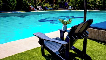 Una piscina al aire libre, sombrillas, sillones reclinables de piscina