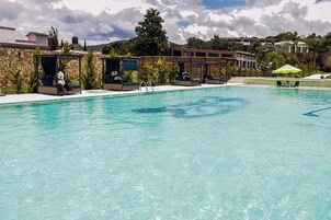 Una piscina con sillones de descanso y un área de estar techada.