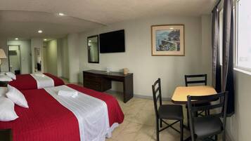 Une chambre d’hôtel avec deux lits, un bureau, une chaise, une télévision et une fenêtre avec des rideaux.