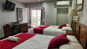 Une chambre d’hôtel avec deux lits, un bureau, une chaise, une télévision et une fenêtre donnant sur un beau paysage.