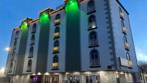 Un hôtel à plusieurs étages, de style architectural classique, doté de balcons et de grandes fenêtres.