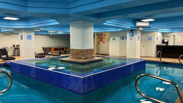 Un espace piscine doté d’une colonne centrale, de chaises longues et d’une table de billard.