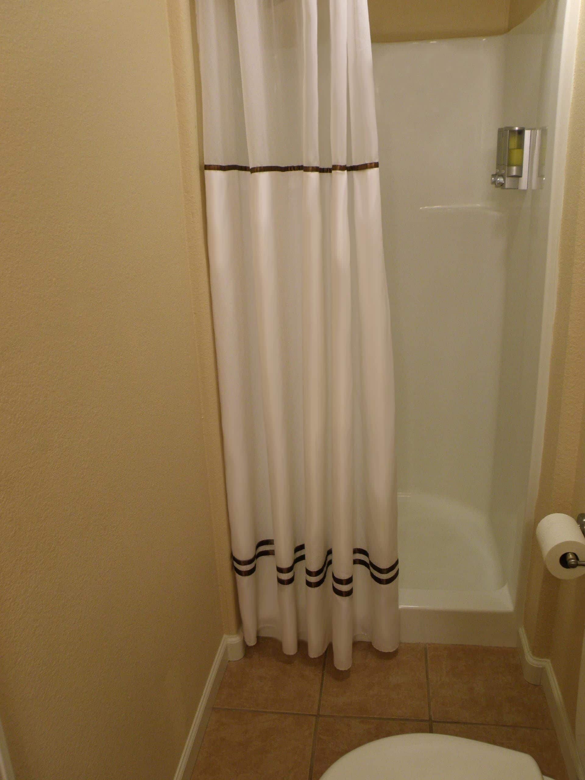 A bathroom with a shower curtain, a toilet, and a bathtub.