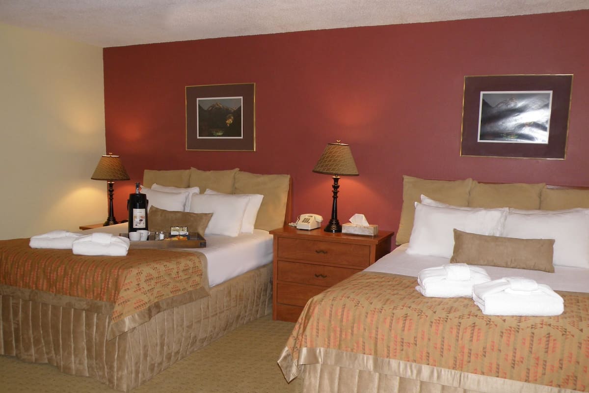Two double beds with matching headboards, bedside tables with lamps, and a small bedside table with a telephone.