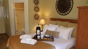 A hotel room with a bed, a bedside table with a coffee maker, a tray with breakfast items, and decorative wall art. - The River's Edge Motel Lodge & Resort (Ouray)