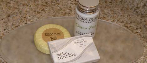 Una barra de mármol blanco, una barra de jabón corporal Terra Pure y una barra de té verde sobre una encimera de granito.