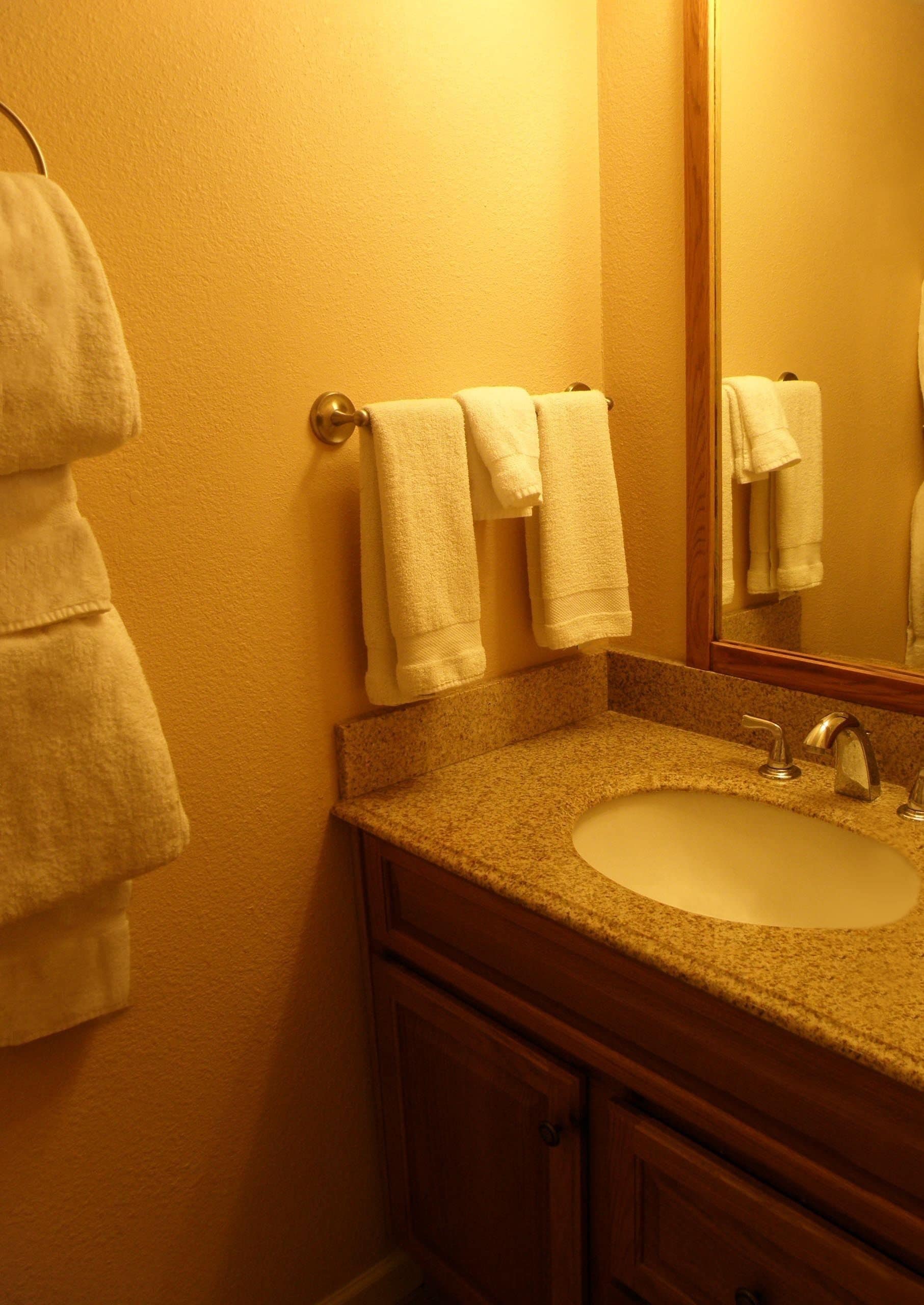 A bathroom with a sink, mirror, and towels.