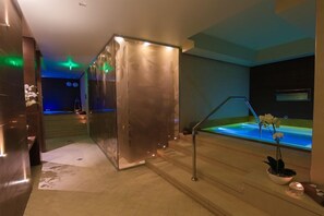 A modern spa area with a glass partition, a heated floor, a small pool, and a staircase leading to a higher level. - Hotel Roman By Dumbrava Business Resort (Roman)