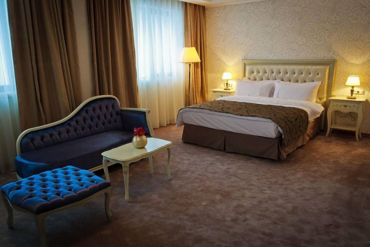 Une chambre d’hôtel avec un lit, un canapé, une petite table et une lampe.