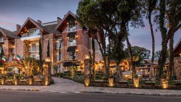 A multi-story hotel with a brick facade, balconies with outdoor seating, and a landscaped entrance.