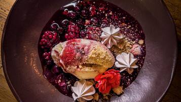 A dessert on a dark plate with berries and decorative elements.