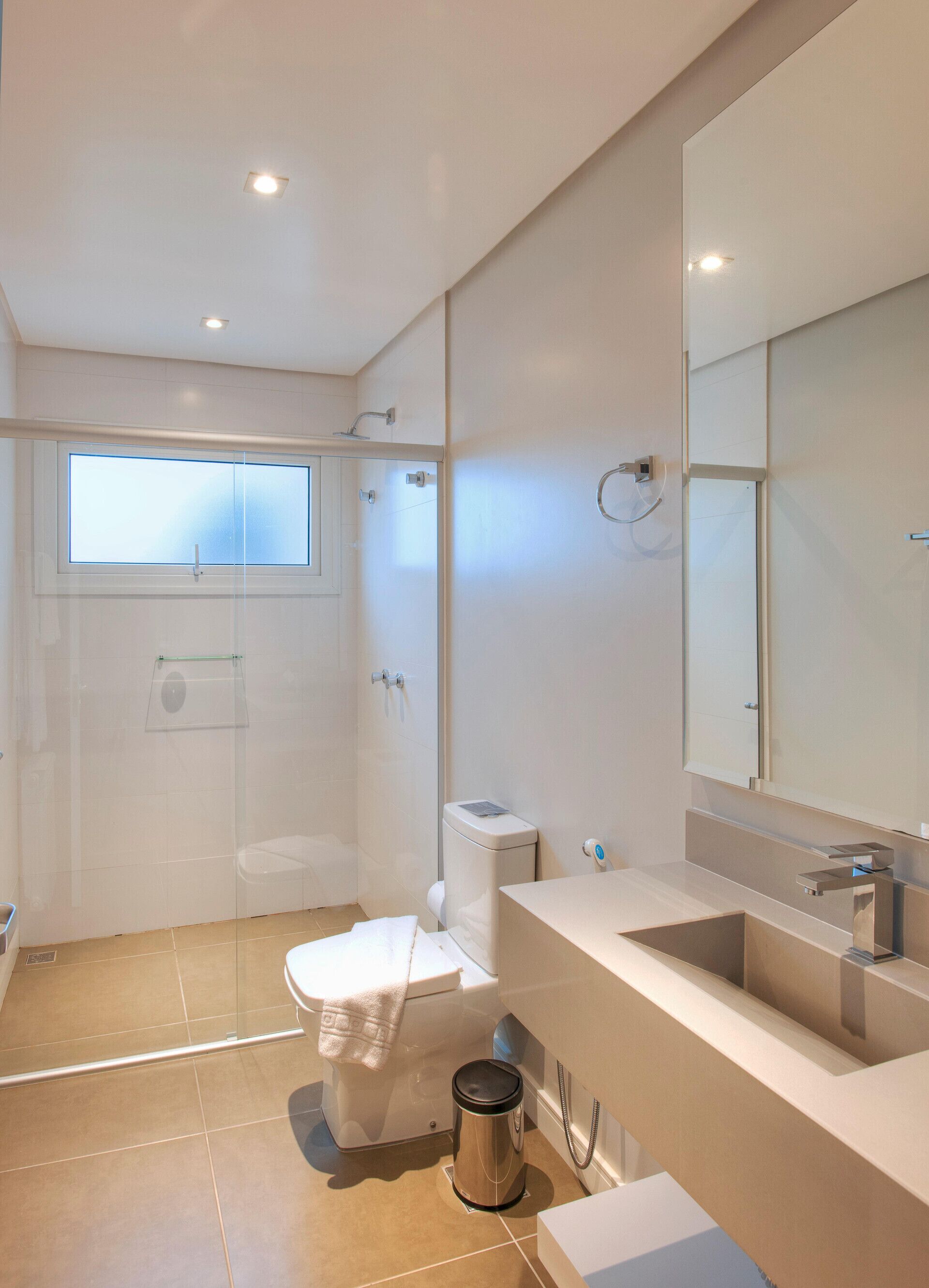 A modern bathroom with a glass shower enclosure, a toilet, a sink, and a large mirror.
