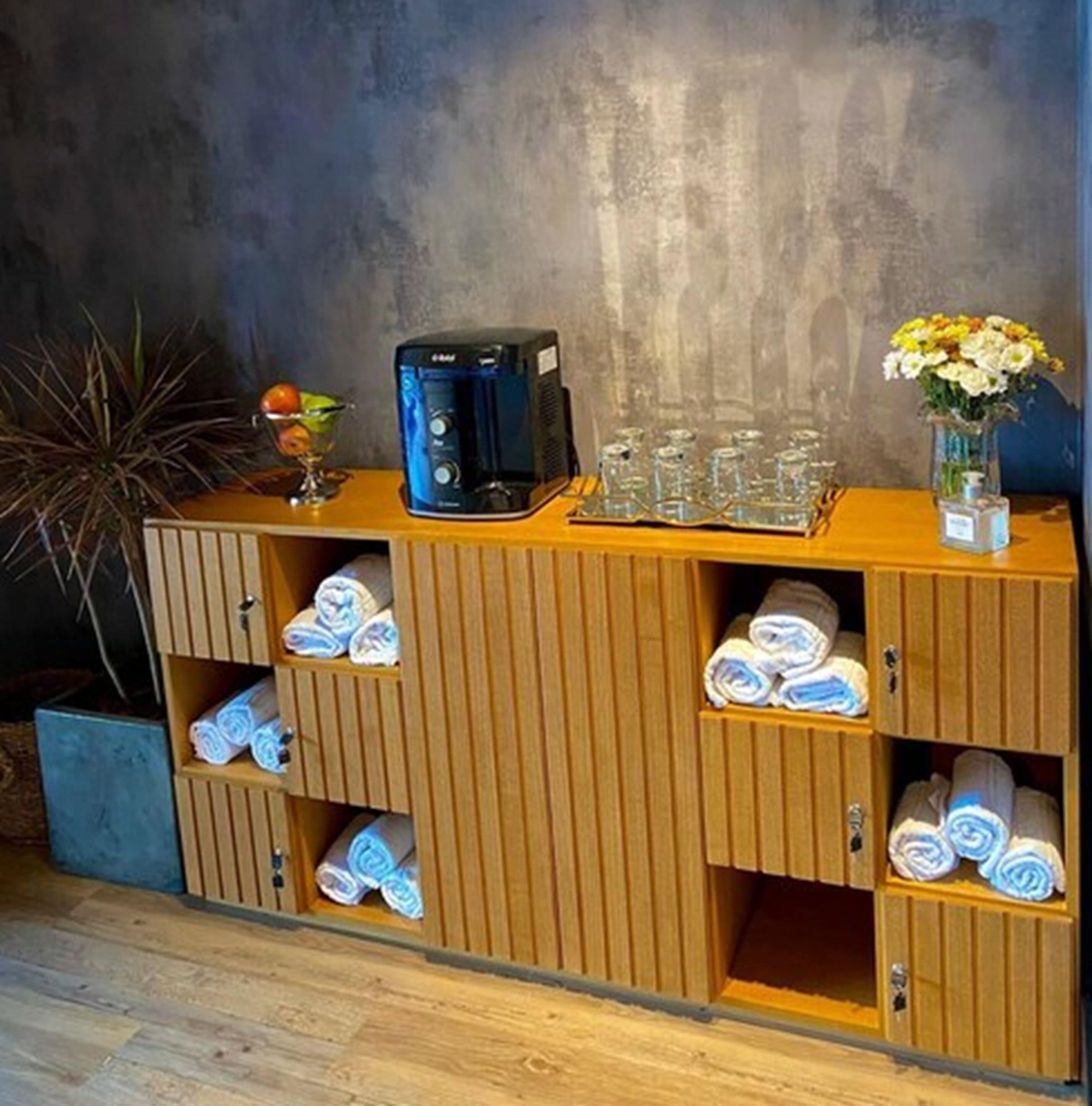 A wooden cabinet with towels and a coffee machine.