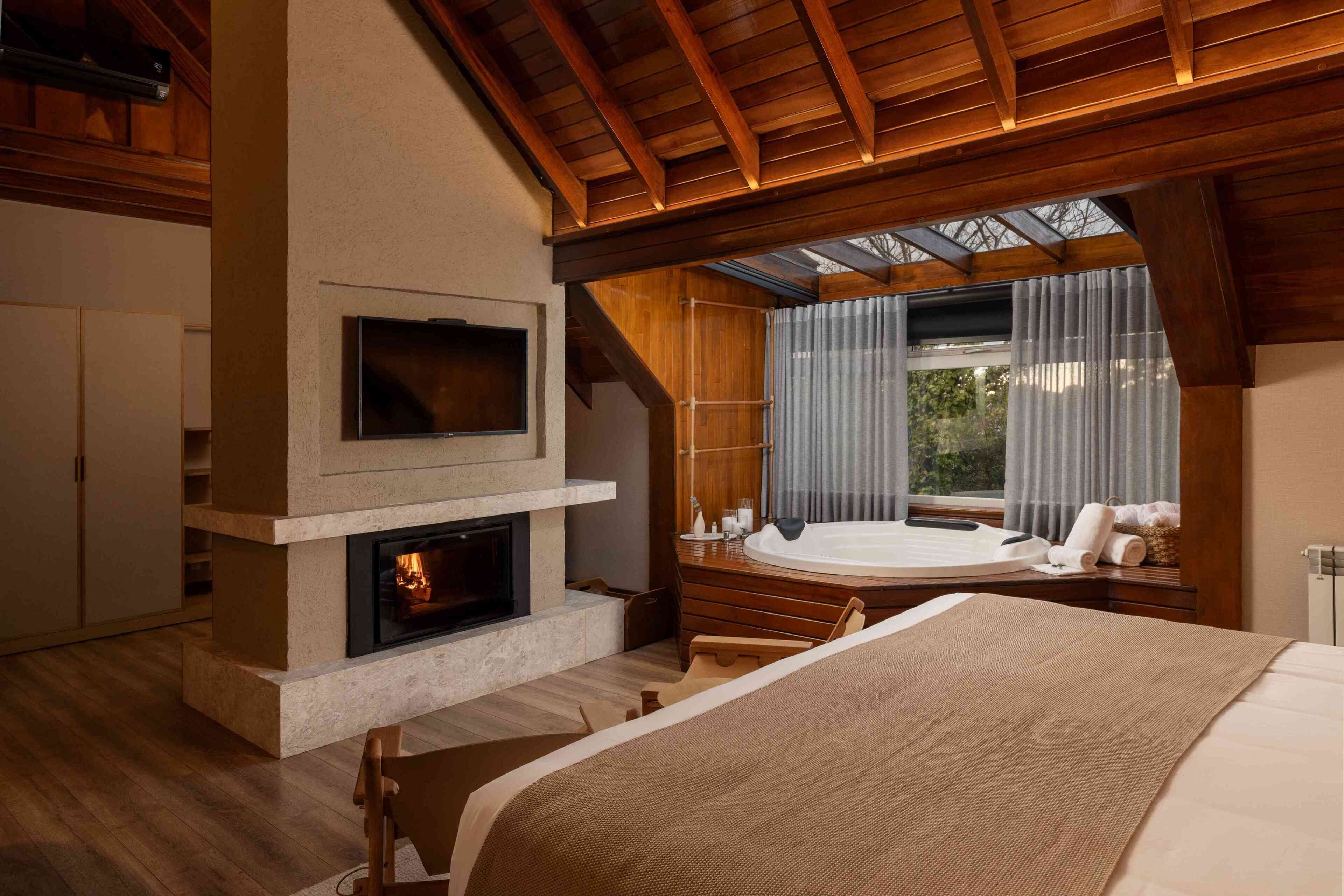Una habitación con chimenea, televisión, bañera de hidromasaje y una cama grande.