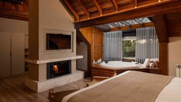 Una habitación con chimenea, televisión, bañera de hidromasaje y una cama grande.