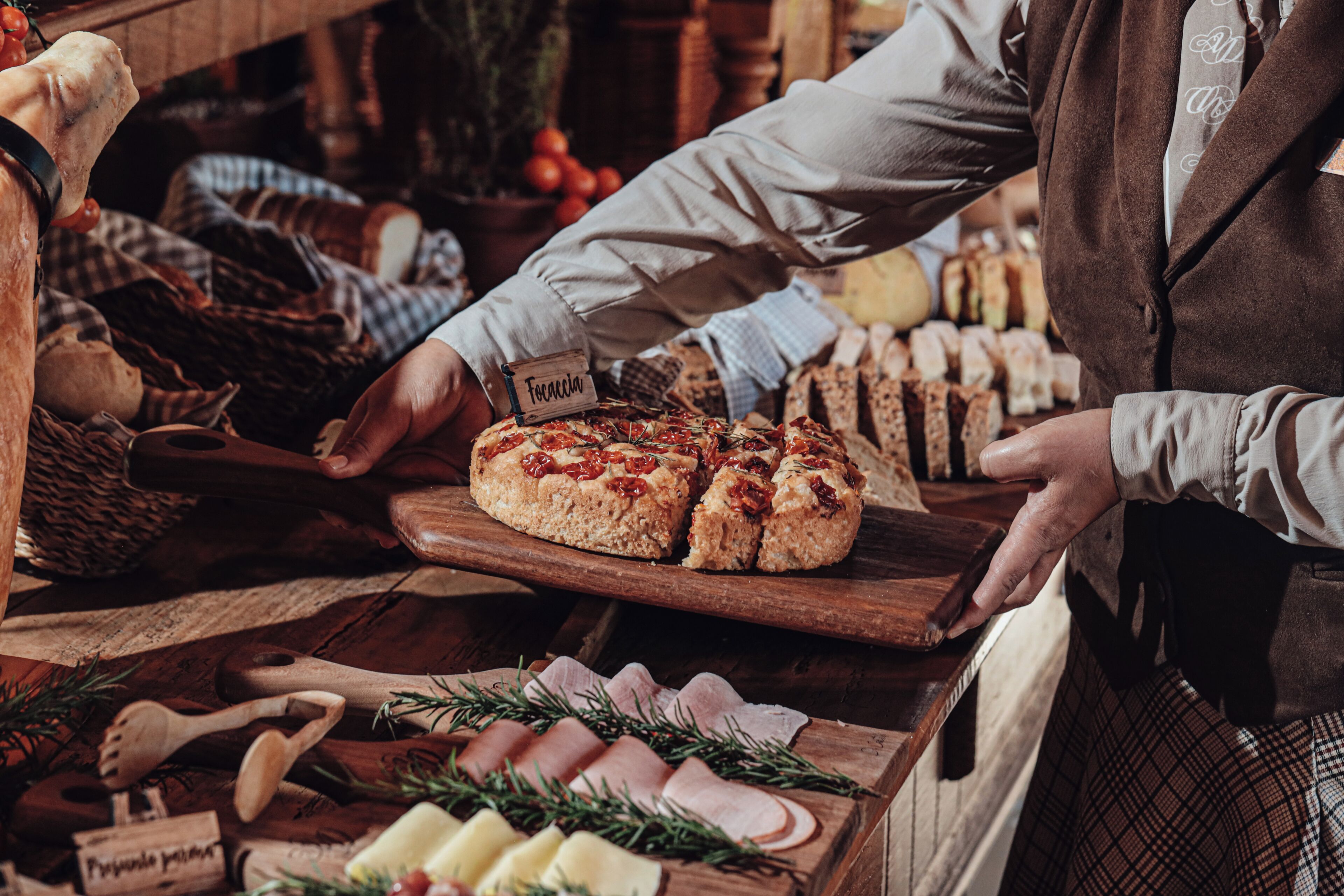 A wooden cutting board with a round loaf of bread, a wooden spoon, and a knife.