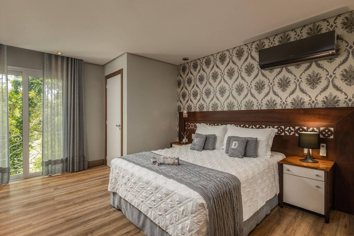 Una habitación de hotel con cama, mesita de noche y aire acondicionado.