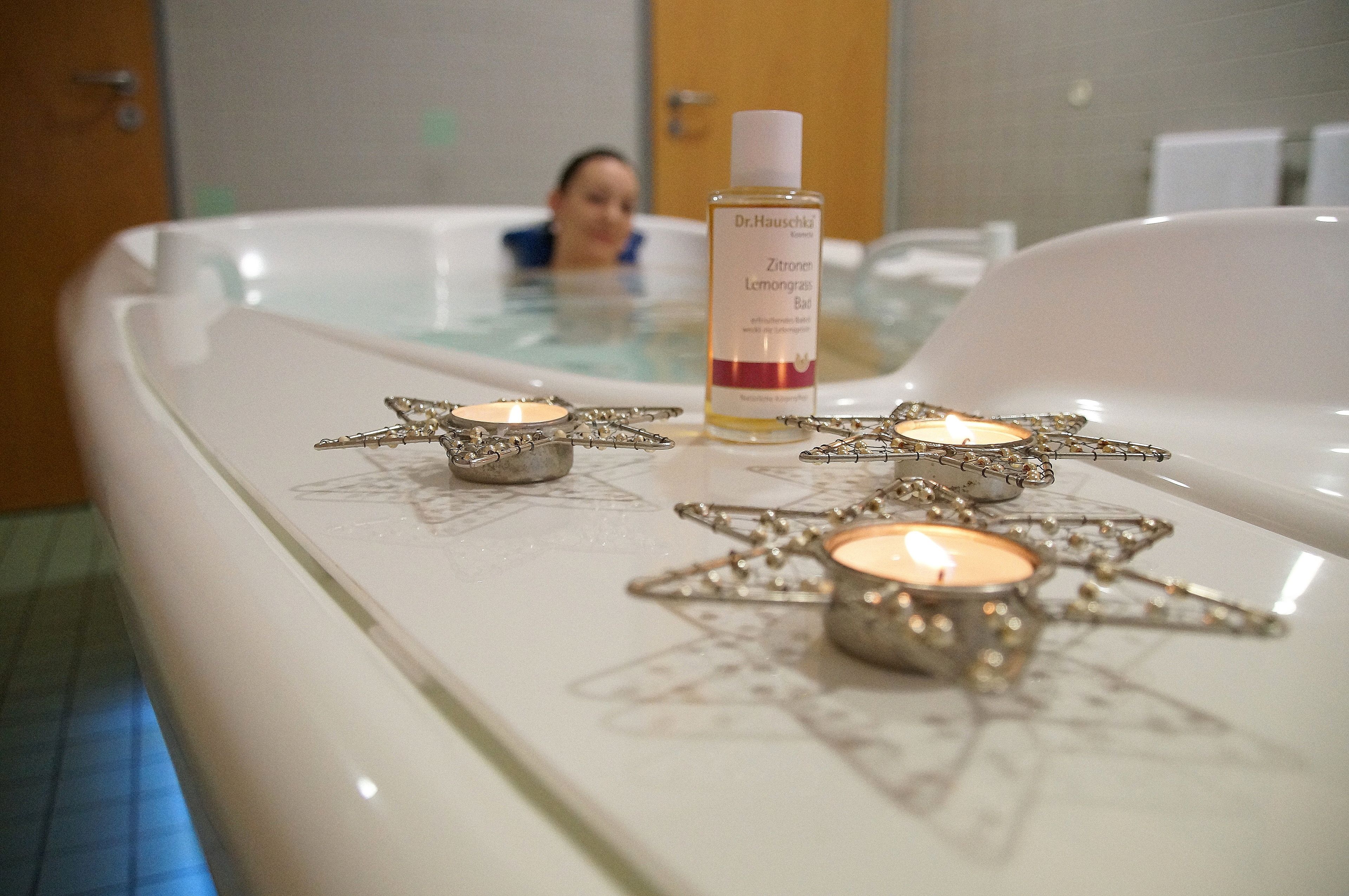 A spa area with a bathtub, candles, and a bottle of Dr. Hauschka Zitrone Limonade Bad.