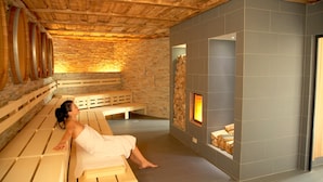 Una sala de sauna con bancos de madera y una pared de piedra con chimenea.