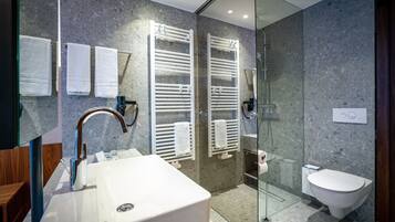 A modern bathroom with a large sink, towel racks, a glass shower enclosure, and a toilet.