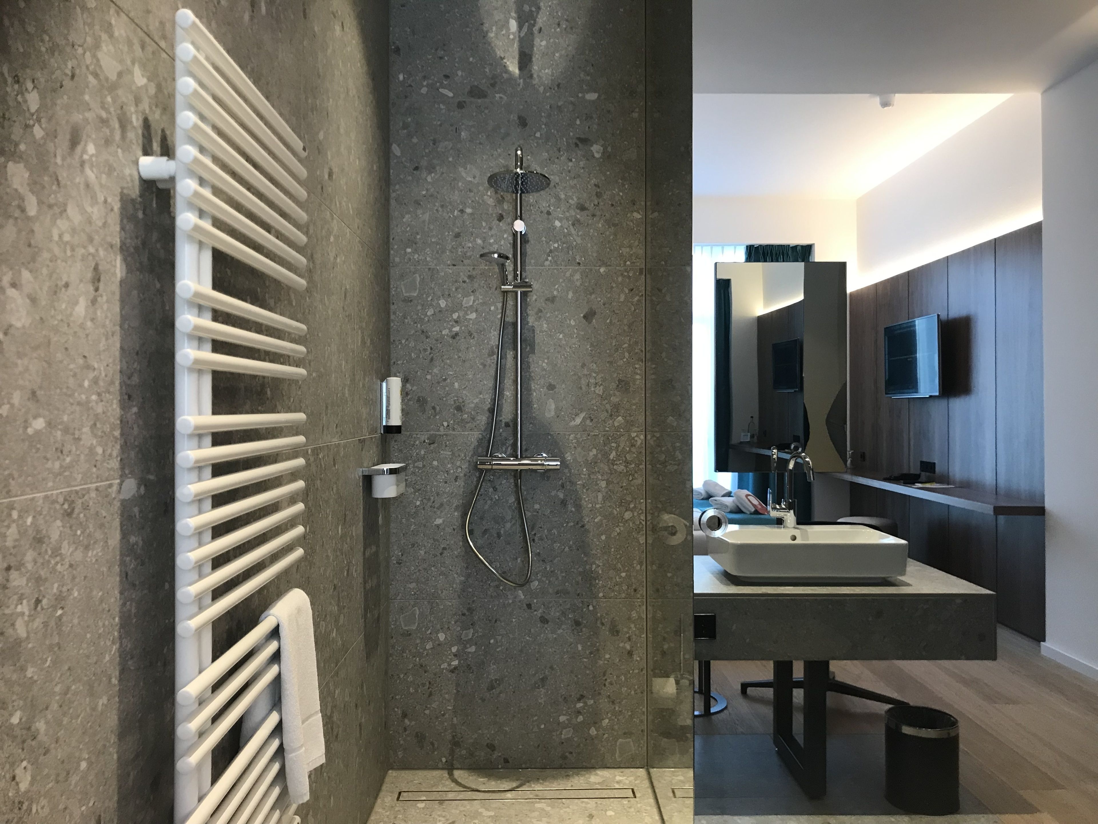 A modern bathroom with a shower, a towel rack, and a sink.