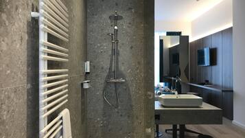 A modern bathroom with a shower, a towel rack, and a sink.