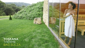 Pared de vidrio con vista a un paisaje verde exuberante y una terraza de madera.
