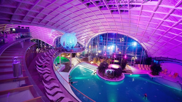 Una piscina interior con techo curvo y varios niveles de asientos.
