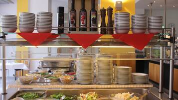 Buffet montado com várias estações de serviço, incluindo saladas, massas e outros pratos, além de bebidas e acompanhamentos.