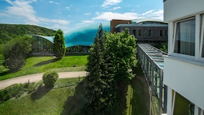 Un edificio moderno con fachada de vidrio, rodeado de exuberante vegetación y un cielo azul despejado.