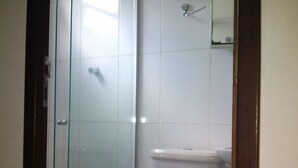 A bathroom with a glass shower enclosure, a toilet, and a sink. - Flat do Indio (Fernando de Noronha)