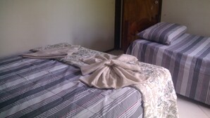 Two single beds with striped bedding, a wooden door, and a plain wall. - Flat do Indio (Fernando de Noronha)