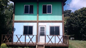 A two-story building with a wooden deck and a metal roof. - Flat do Indio (Fernando de Noronha)