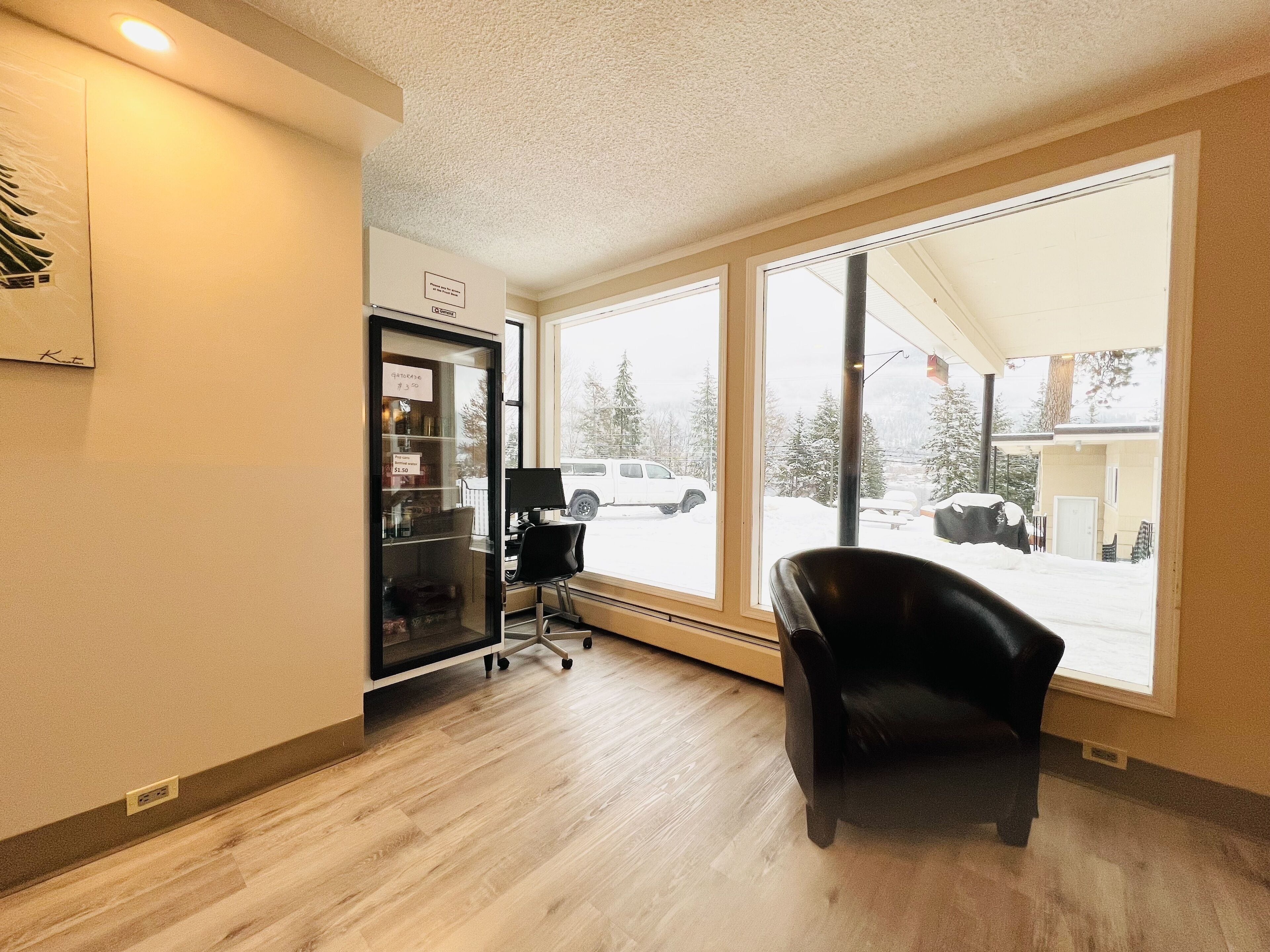 A room with a large window, a black office chair, and a vending machine.