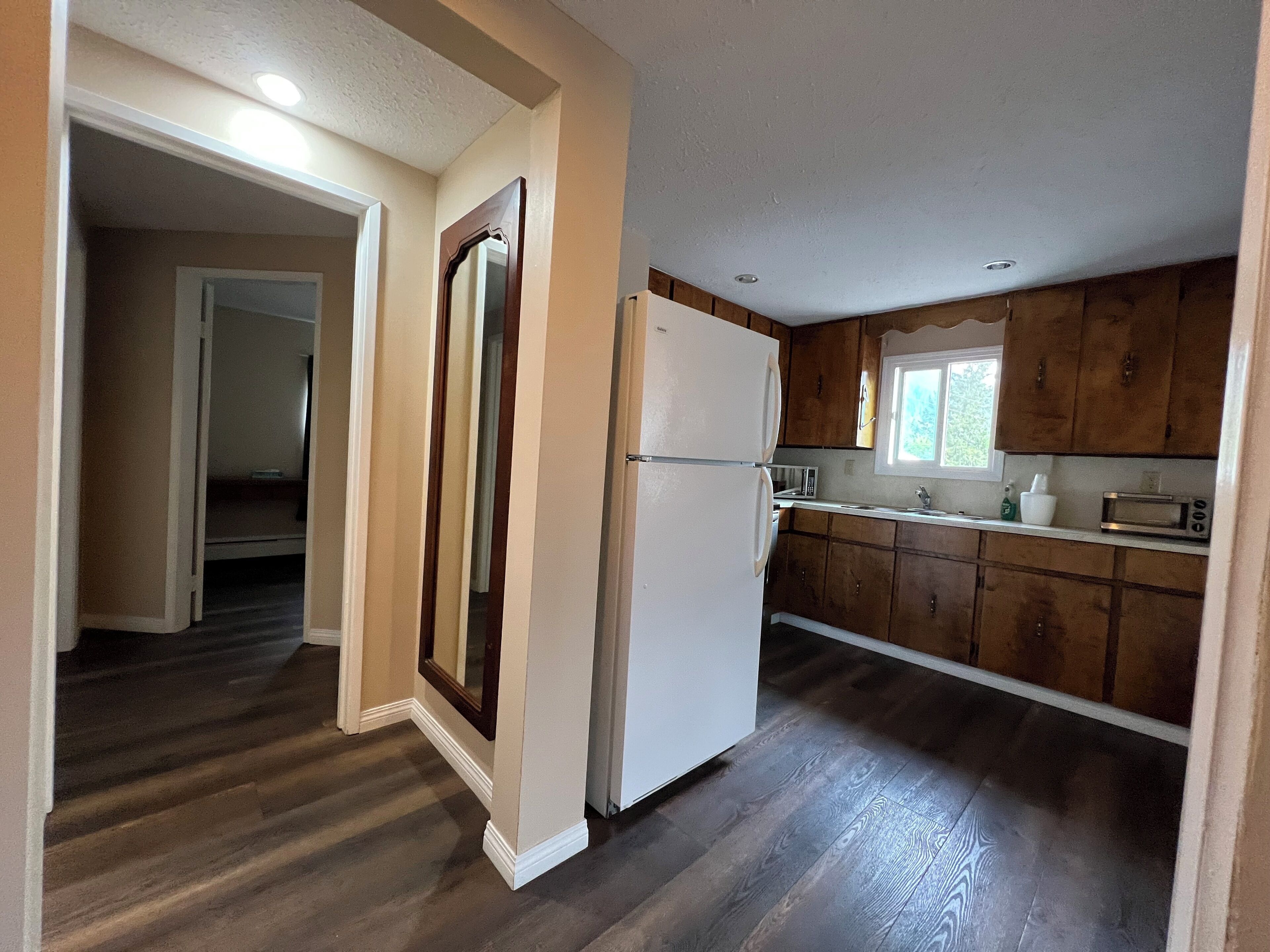 A kitchen with wooden cabinets, a white refrigerator, and a microwave.