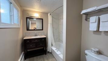 Un baño con tocador, bañera, inodoro y cortina de ducha.