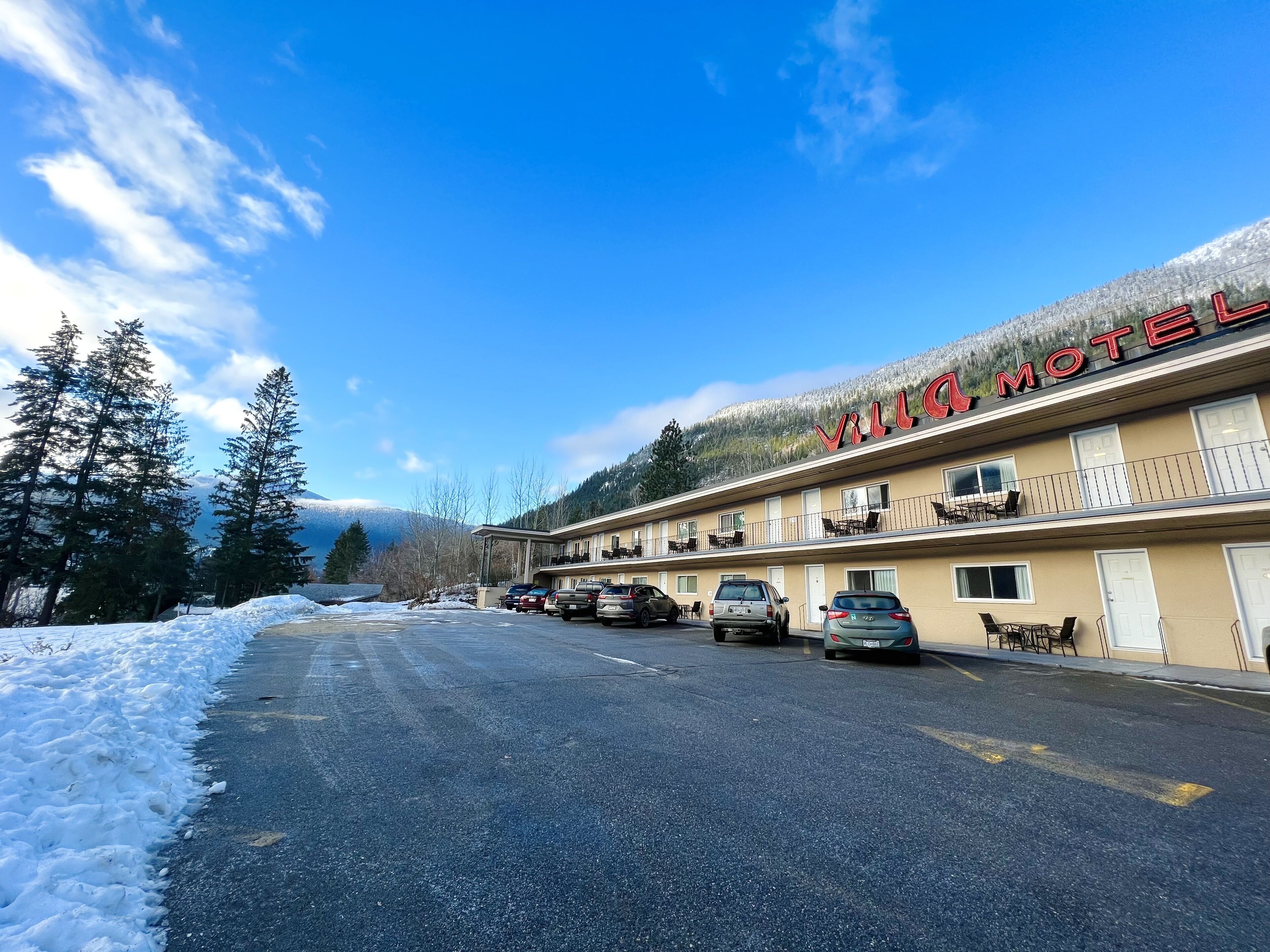 Un motel con un letrero que dice 'Villa Motel' y un estacionamiento con varios autos.
