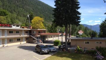 Un motel con estacionamiento, una escalera que lleva a la entrada y montañas al fondo.