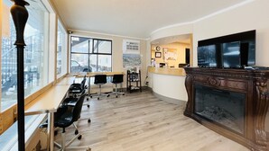 A modern office space with a reception desk, a fireplace, and large windows offering views of the outside. - Villa Motel (Nelson)