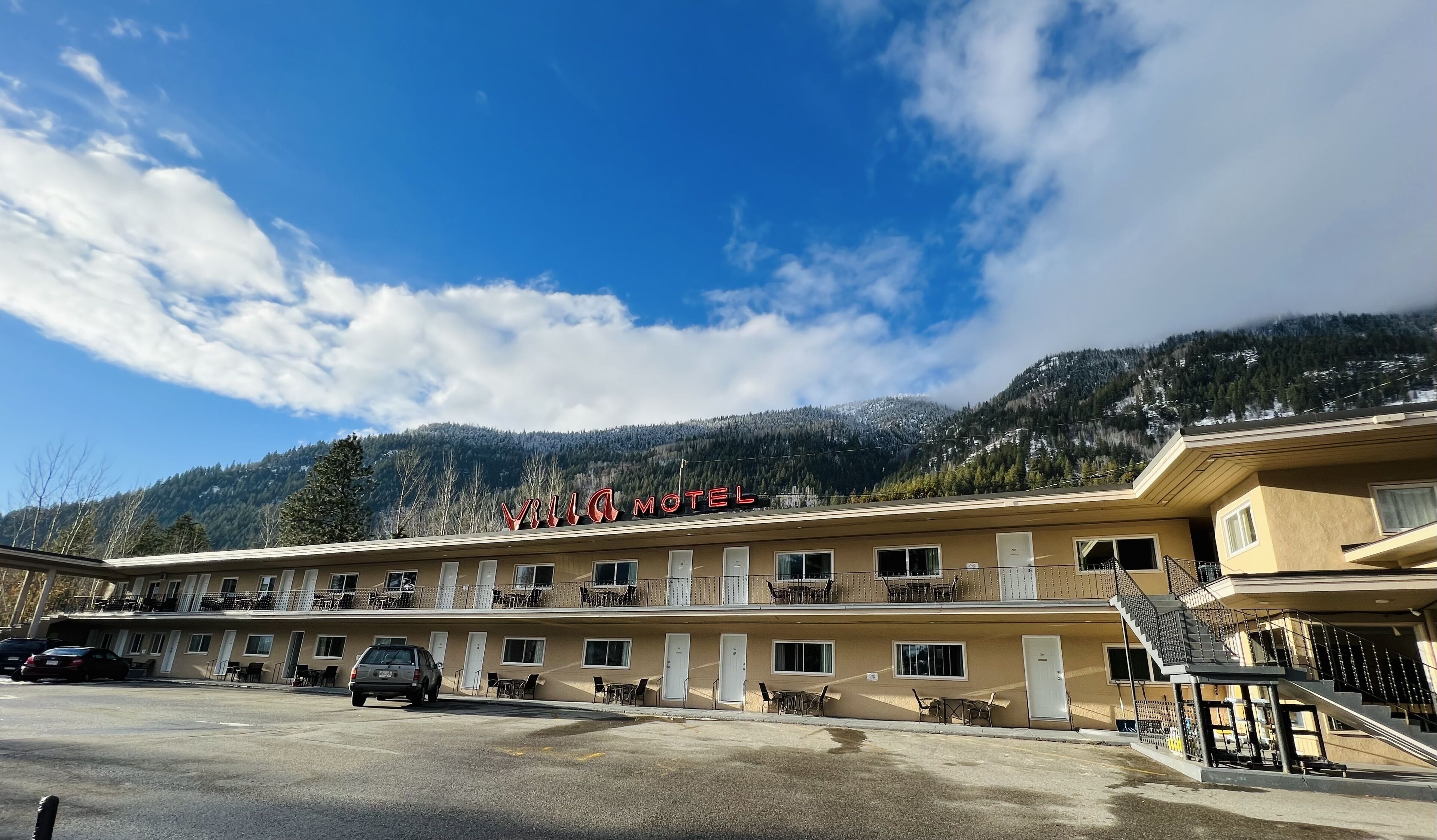 Un motel avec une enseigne indiquant « Villa Motel », sur fond de montagnes et sous un ciel dégagé.
