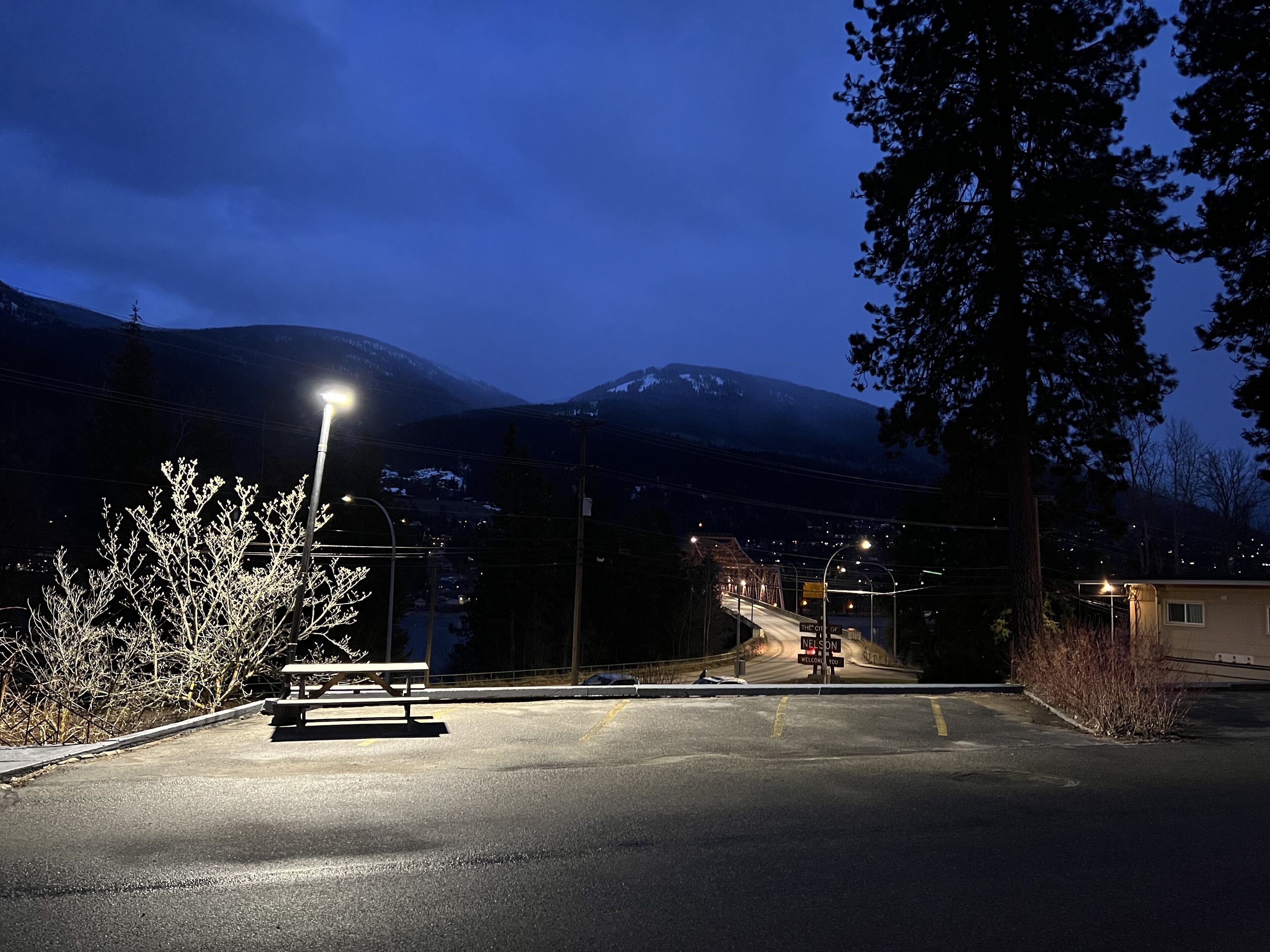 Un espace de stationnement équipé d’une table de pique-nique, de lampadaires et d’une route menant à la montagne.