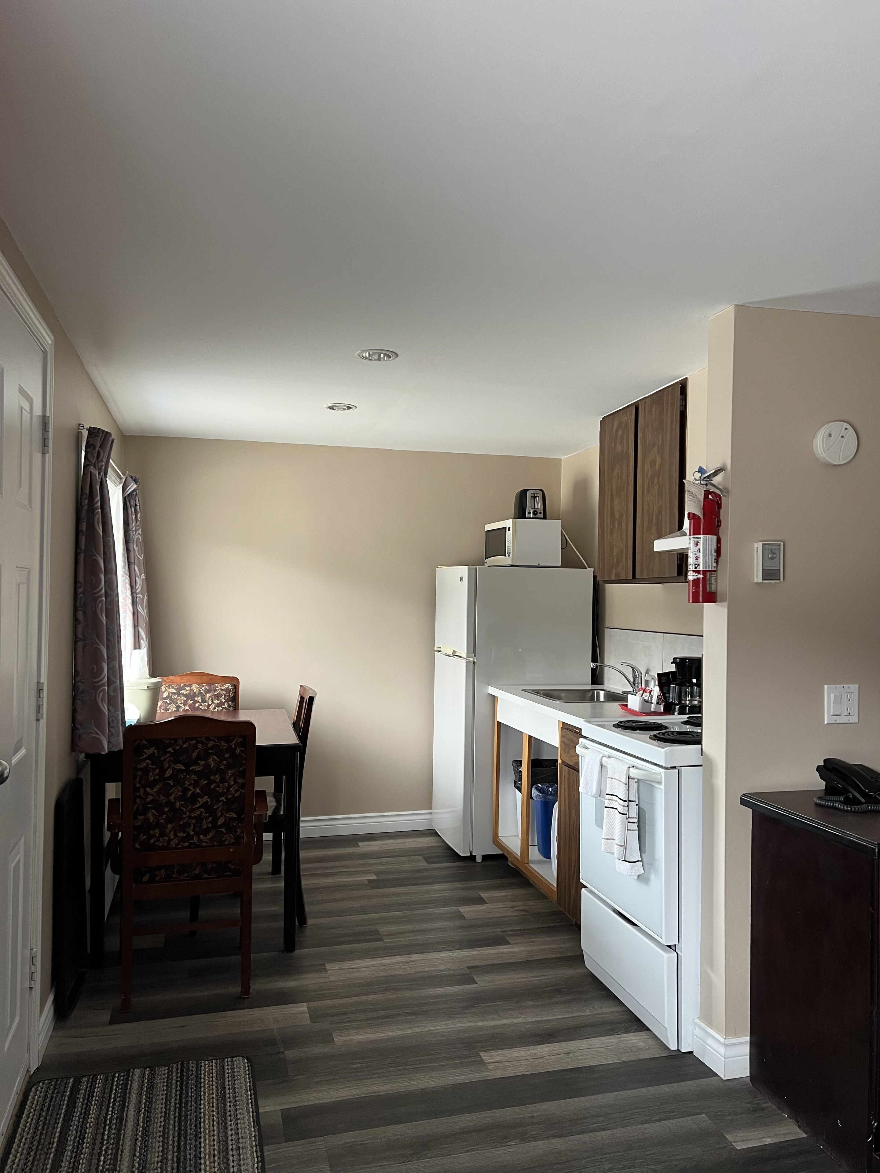 A compact kitchen with a refrigerator, microwave, stove, and sink.