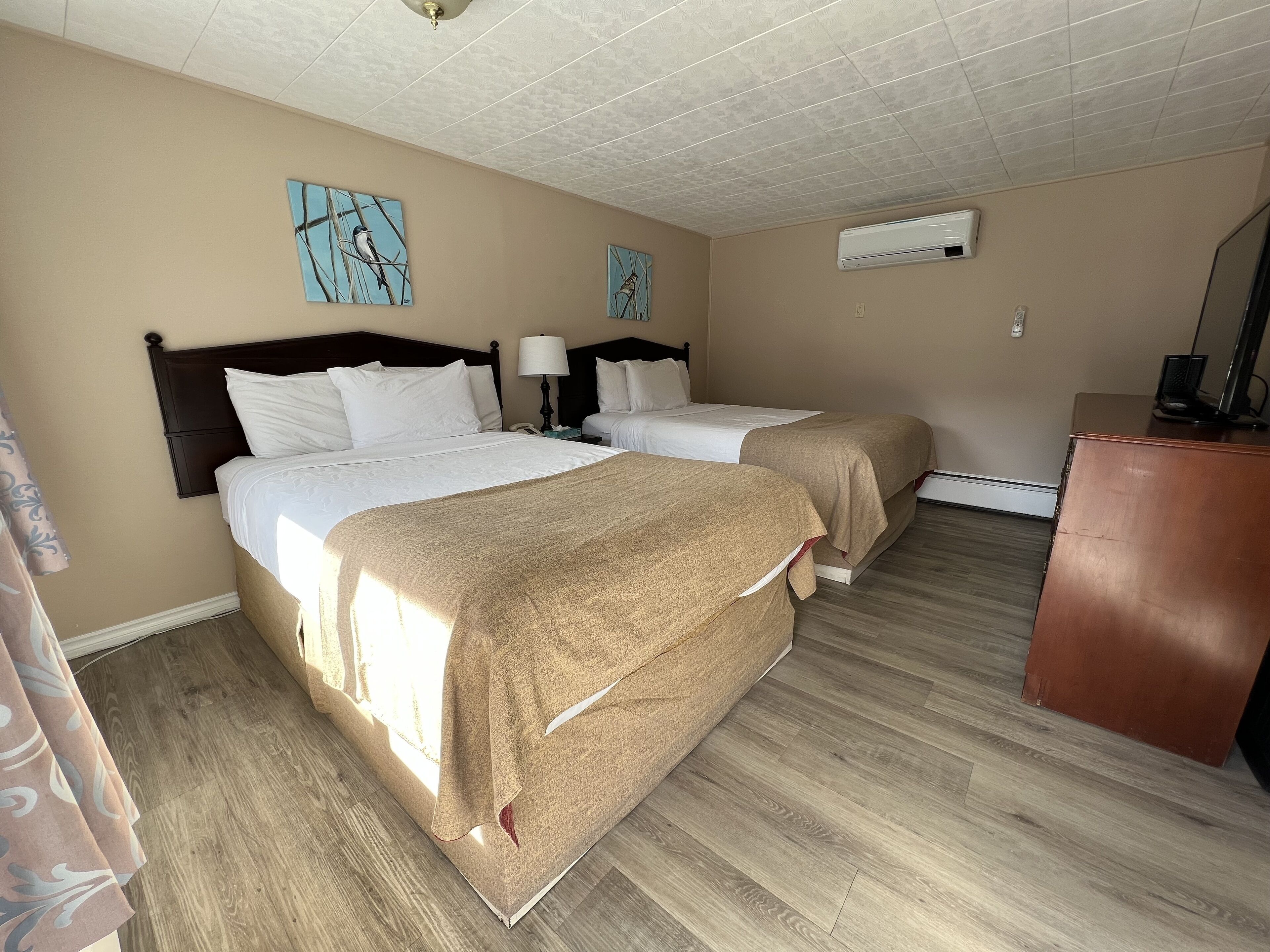 A hotel room with two beds, a desk, and a ceiling fan.
