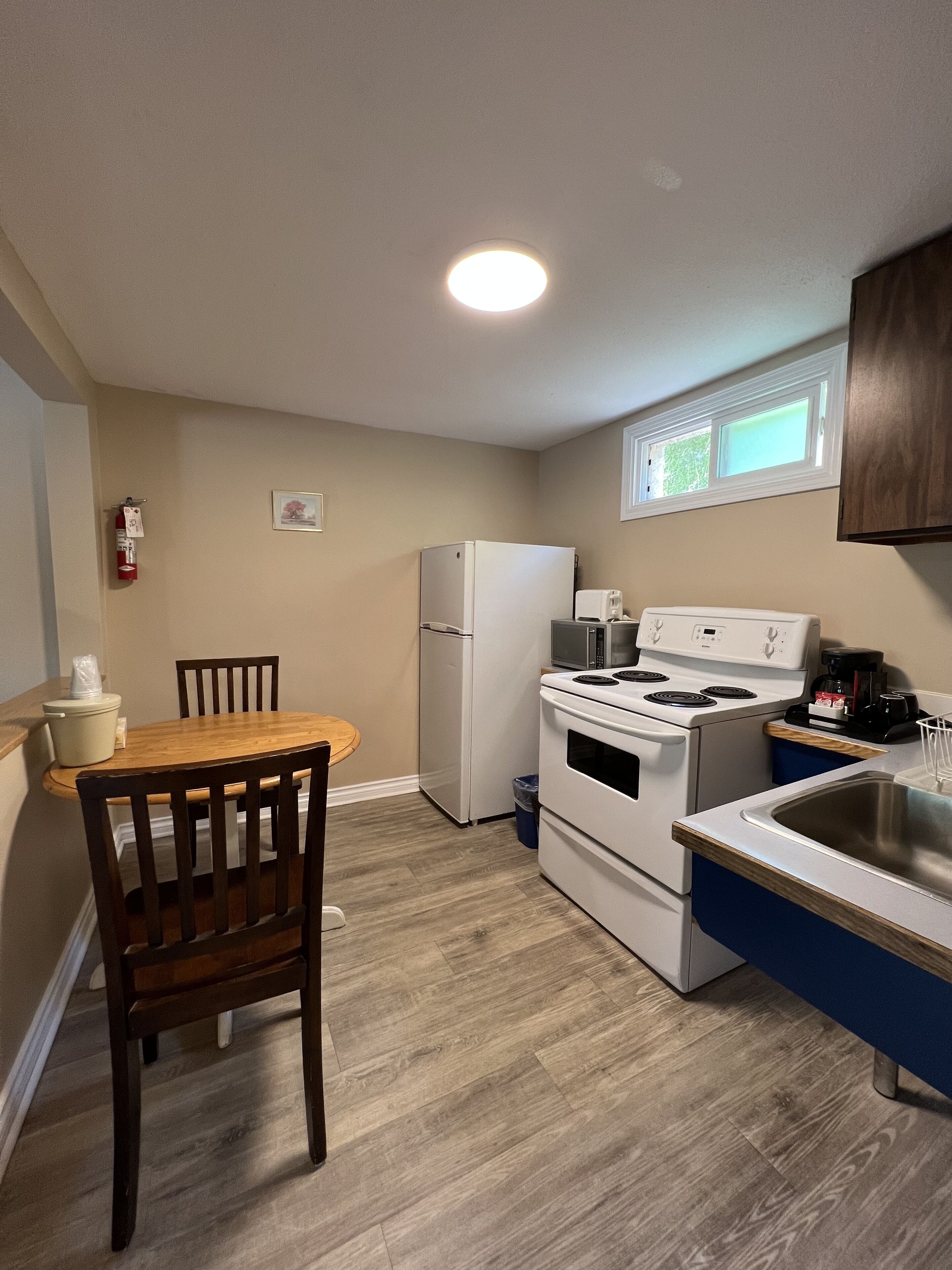 A compact kitchen with a refrigerator, stove, microwave, and sink.