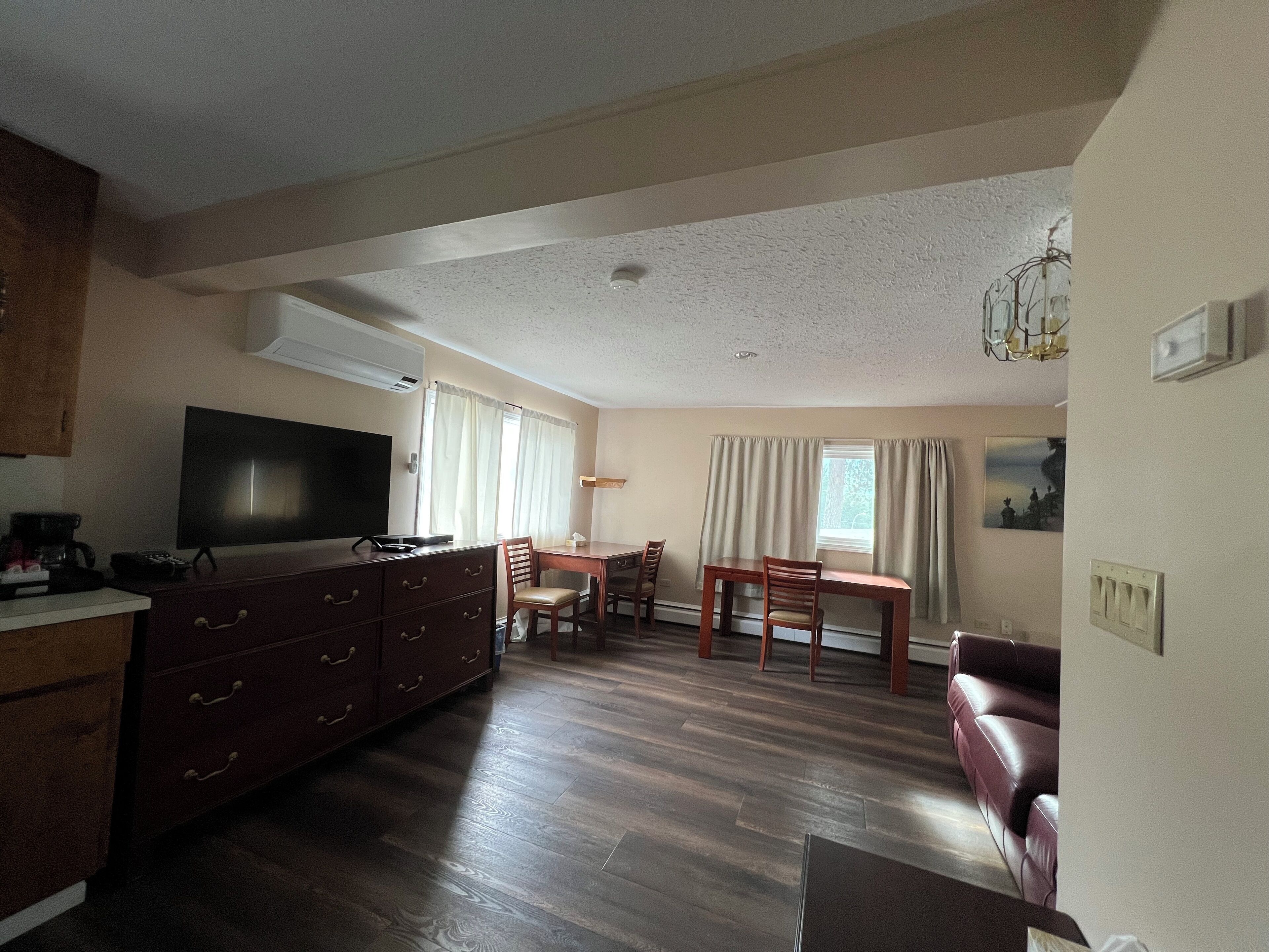 A spacious living room with a large flat-screen TV, wooden furniture, and a dining area.